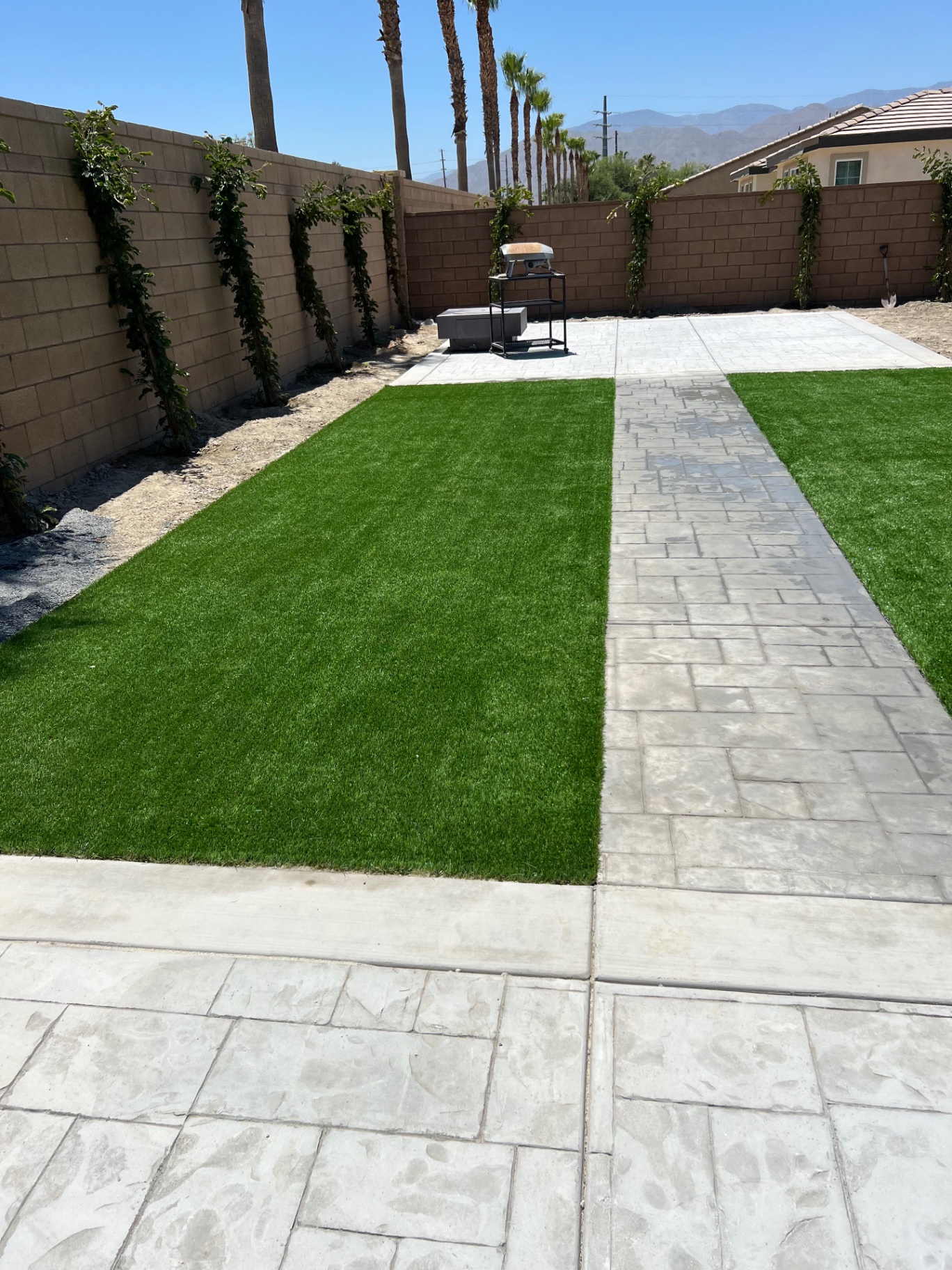 Artificial turf side yard split by stamped concrete walkway